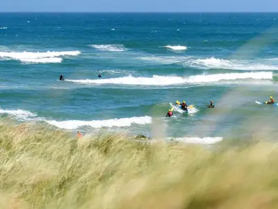 a group of people riding the waves in the ocean at Holiday Home Arngrim - 100m from the sea by Interhome in Torsted