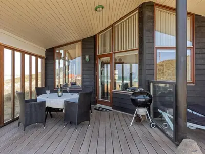 a porch with a grill and a table and chairs at Holiday Home Arngrim - 100m from the sea by Interhome in Torsted