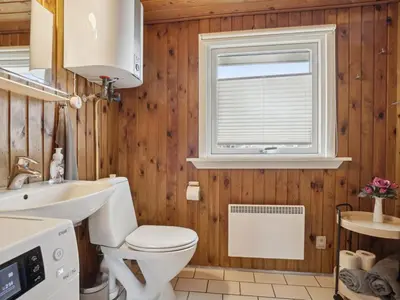 a bathroom with a toilet and a sink and a window at Holiday Home Siri - 400m from the sea by Interhome in Thisted