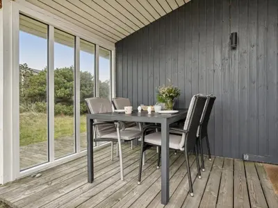 a dining room table and chairs on a porch at Holiday Home Siri - 400m from the sea by Interhome in Thisted
