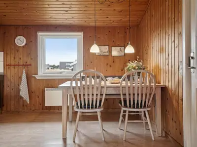 two chairs at a table in a kitchen with wooden walls at Holiday Home Siri - 400m from the sea by Interhome in Thisted
