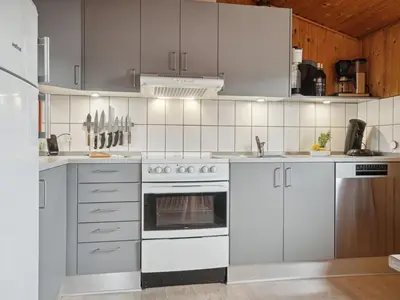 a kitchen with white appliances and wooden cabinets at Holiday Home Siri - 400m from the sea by Interhome in Thisted