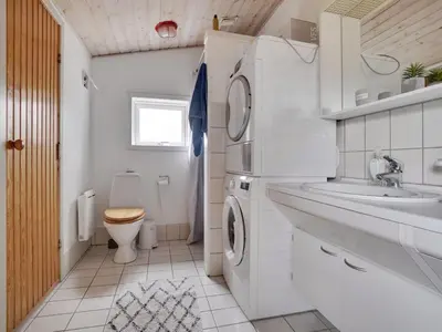 a bathroom with a washing machine and a sink and a toilet at Holiday Home Gottliebe - 850m from the sea by Interhome in Torsted