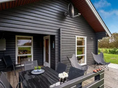 a black house with a table and chairs on a deck at Holiday Home Engeline - 300m to the fjord by Interhome in Vemb