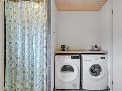 a laundry room with a washing machine and a shower curtain at Holiday Home Daina - 400m to the fjord by Interhome in Vemb