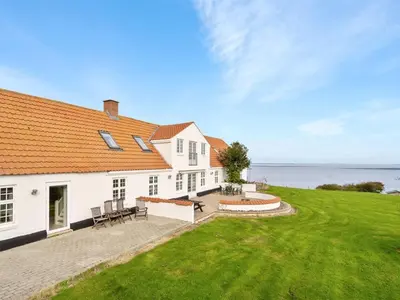a large white house with a patio and a lawn at Holiday Home Thorge - 75m to the fjord by Interhome in Struer