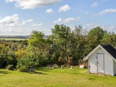 a small white shed in a field with trees at Holiday Home Tomine - 500m to the fjord by Interhome in Struer
