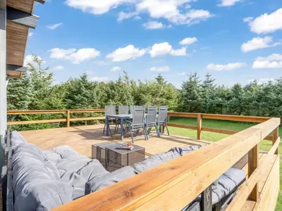 a wooden deck with a couch and a table at Holiday Home Matilde - 400m to the fjord by Interhome in Struer