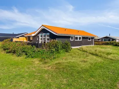 a house with an orange roof on a green field at Holiday Home Marissa - 200m from the sea by Interhome in Torsted
