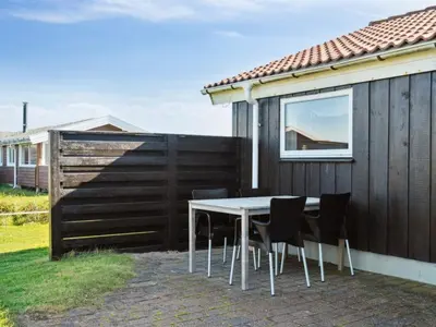 a table and chairs on a patio next to a fence at Holiday Home Marissa - 200m from the sea by Interhome in Torsted