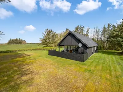 a small black building in a field with trees at Holiday Home Aleida - 100m to the fjord by Interhome in Vemb