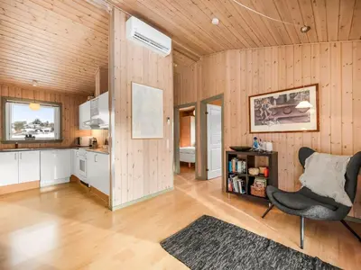 a living room with a chair and a kitchen at Holiday Home Kai - 500m to the fjord by Interhome in Struer