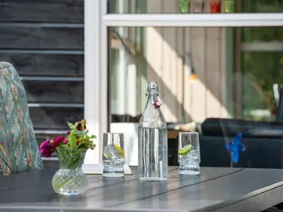 a table with a bottle and three glasses on it at Holiday Home Kai - 500m to the fjord by Interhome in Struer