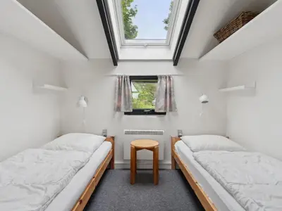 two beds in a room with a window and a table at Holiday Home Biriel - 1km from the sea by Interhome in Thisted