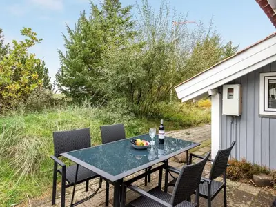 a table and chairs on a patio with a bottle of wine at Holiday Home Biriel - 1km from the sea by Interhome in Thisted