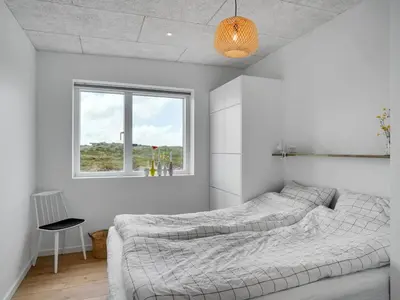 a white bedroom with two beds and a window at Holiday Home Trpana - 1-6km from the sea by Interhome in Thisted