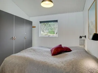 a bedroom with a bed with a red pillow on it at Holiday Home Ljupka - 1km from the sea by Interhome in Thisted
