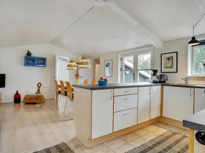 a kitchen with white cabinets and a dining room at Holiday Home Ljupka - 1km from the sea by Interhome in Thisted