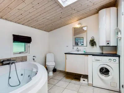 a bathroom with a tub and a washing machine at Holiday Home Emeline - 1-7km from the sea by Interhome in Thisted