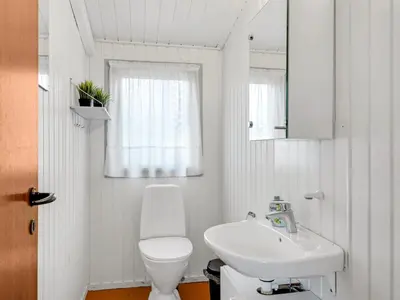 a white bathroom with a toilet and a sink at Holiday Home Gundina - 2km from the sea by Interhome in Thisted