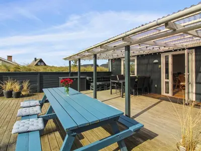 a blue picnic table on a deck with a pergola at Holiday Home Madsen - 500m from the sea by Interhome in Thisted