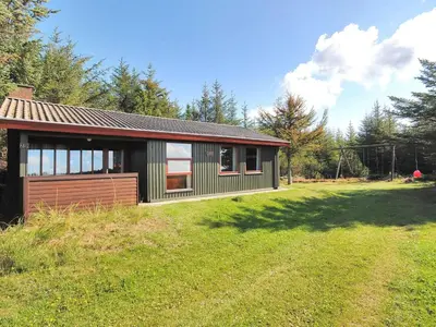a small house on a grassy field next to a forest at Holiday Home Neven - 900m from the sea by Interhome in Torsted
