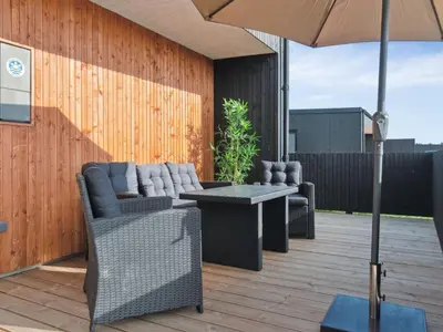 a patio with a table and chairs and an umbrella at Holiday Home Kasper - 1-8km from the sea by Interhome in Thisted