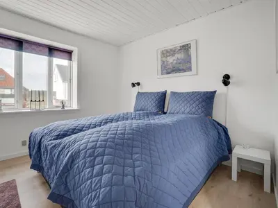 a bed in a white bedroom with a blue comforter at Holiday Home Thilla - 100m from the sea by Interhome in Thisted