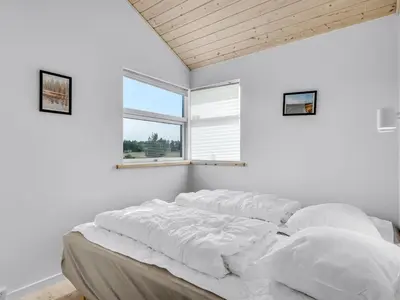 a bedroom with white walls and a bed with pillows at Holiday Home Sulki - 3-5km from the sea by Interhome in Frøstrup