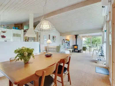 a kitchen and dining room with a wooden table and chairs at Holiday Home Aameek - 3km from the sea by Interhome in Frøstrup