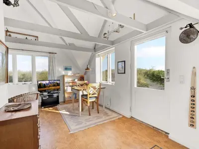 a living room with white walls and a table and chairs at Holiday Home Ebba - 25m from the sea by Interhome in Frøstrup