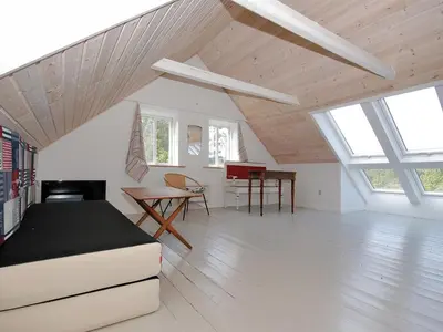 a attic room with a bed and a table at Holiday Home Margrethe - 1-1km from the sea by Interhome in Bedsted Thy