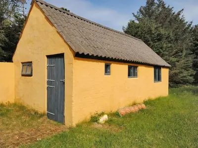 a yellow building with a black door in a field at Holiday Home Margrethe - 1-1km from the sea by Interhome in Bedsted Thy