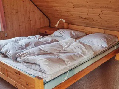 an unmade bed in a room with a wooden wall at Holiday Home Simo - 250m from the sea by Interhome in Øsløs