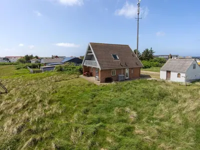 a house on top of a grassy hill at Holiday Home Bjarnger - 200m from the sea by Interhome in Frøstrup