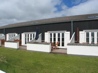 a black building with a deck and a house at Apartment Ingeborre - 100m to the fjord by Interhome in Vestervig