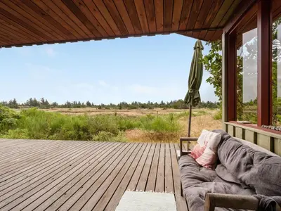 a couch on a porch with a view of a field at Holiday Home Atreju - 2km from the sea by Interhome in Bedsted Thy