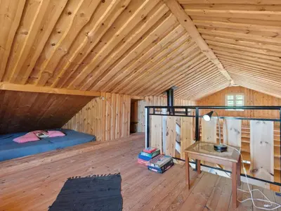 a bedroom in a wooden cabin with a bed and a table at Holiday Home Elsia - 1-5km to the fjord by Interhome in Frøstrup