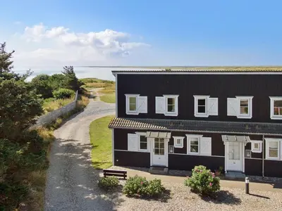 a black and white house with a road next to it at Apartment Hubertine - 100m to the fjord by Interhome in Vestervig