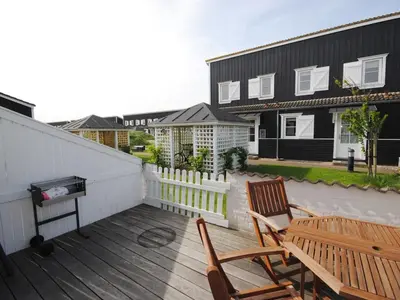 a wooden deck with two chairs and a grill at Apartment Stelle - 100m to the fjord by Interhome in Vestervig