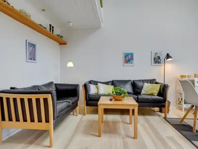 a living room with a black leather couch and a table at Apartment Tofan - 100m to the fjord by Interhome in Vestervig
