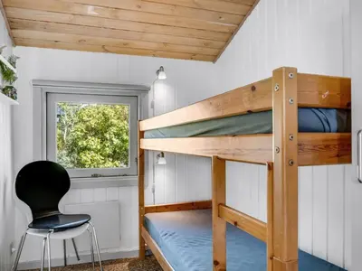 a small bedroom with a bunk bed and a chair at Holiday Home Sulevi - 200m to the fjord by Interhome in Vestervig