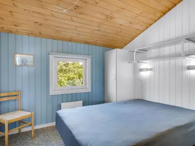 a bedroom with a bed and a window and a chair at Holiday Home Sulevi - 200m to the fjord by Interhome in Vestervig