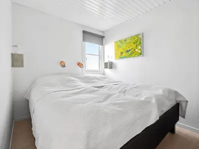 a white bedroom with a large bed with a window at Apartment Hermanda - 100m to the fjord by Interhome in Vestervig