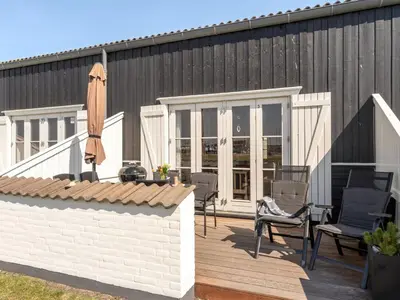 a deck with chairs and an umbrella on a building at Apartment Idunn - 100m to the fjord by Interhome in Vestervig
