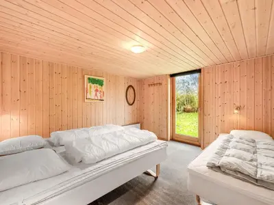 two beds in a room with wooden walls and a window at Holiday Home Scarlet - 400m to the fjord by Interhome in Vinderup