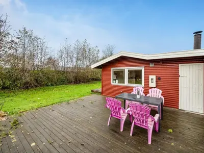 a deck with pink chairs and a table and a house at Holiday Home Scarlet - 400m to the fjord by Interhome in Vinderup
