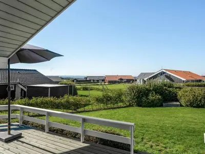 a porch with a white fence and an umbrella at Holiday Home Brynjolf - 350m to the fjord by Interhome in Vinderup