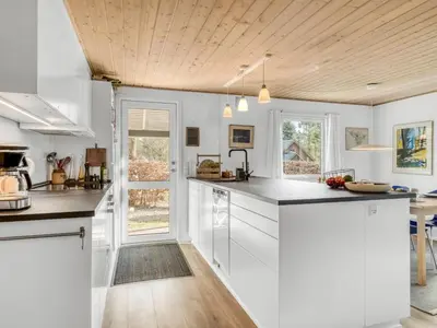 a kitchen with white cabinets and a wooden ceiling at Holiday Home Milan - 250m to the fjord by Interhome in Thyholm