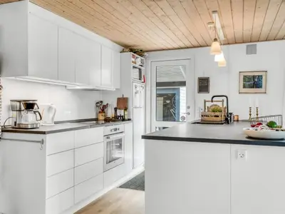 a kitchen with white cabinets and a black counter top at Holiday Home Milan - 250m to the fjord by Interhome in Thyholm